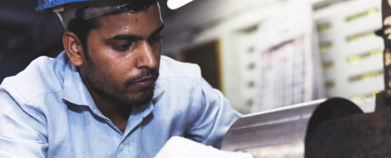 Indian engineer at a steel mill factory planning the use of a piece of a metal pipe.