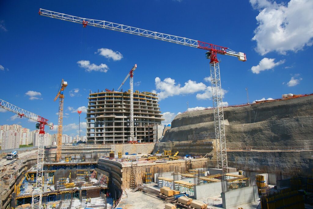 A building construction site with several cranes and blocks of flats in the background. 