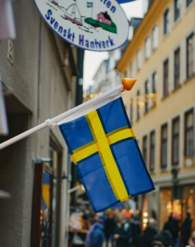 A Swedish flag hanging from a building on a busy street in Sweden.