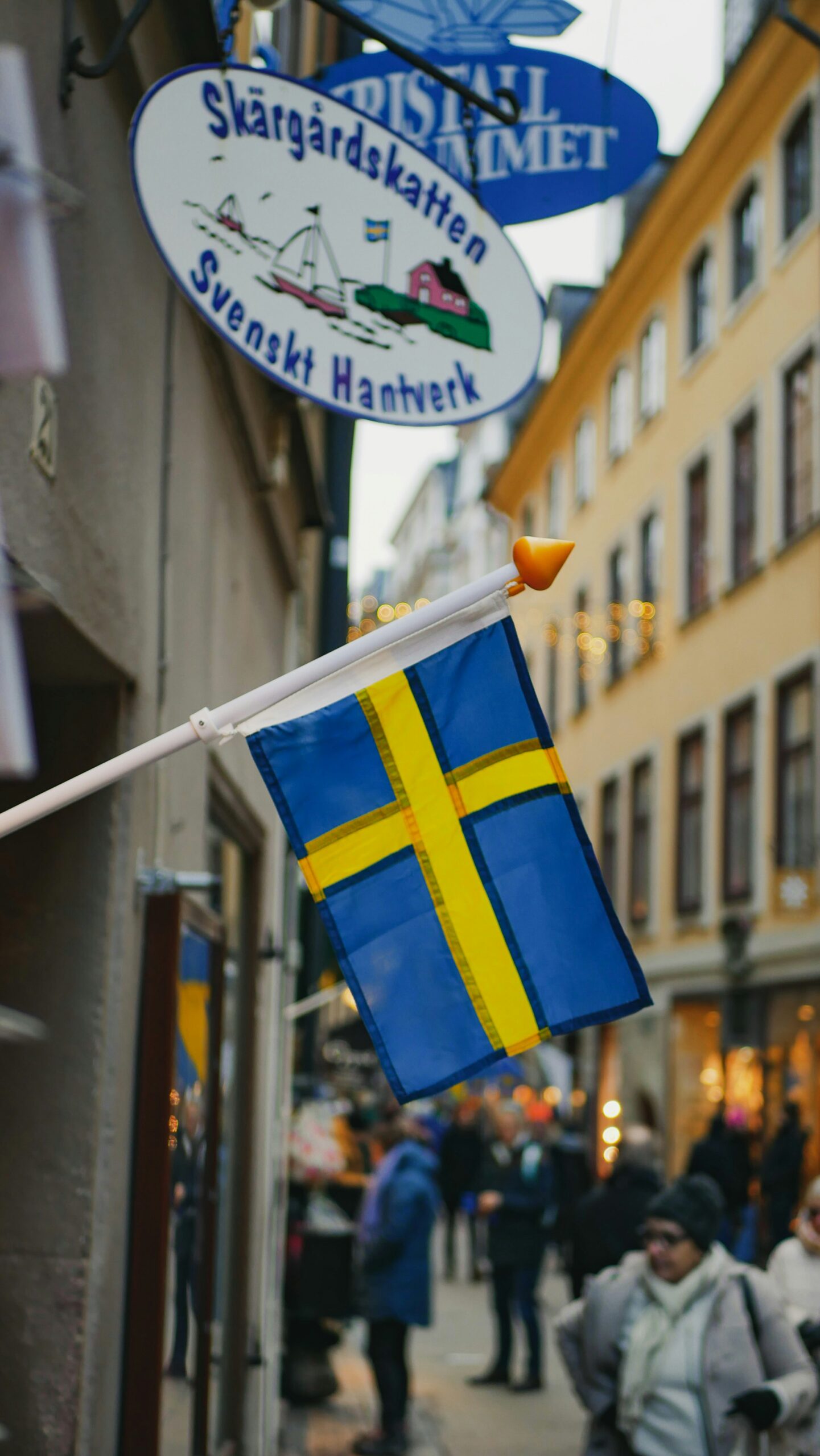 A Swedish flag hanging from a building on a busy street in Sweden.